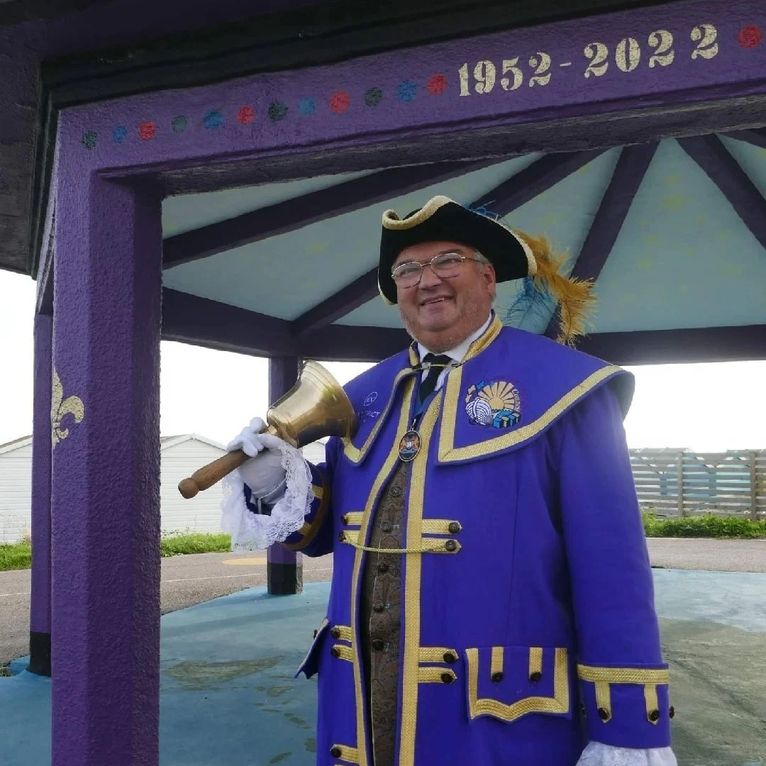 Bob Smytherman in the purple robes of the Adur office, bell in hand, beneath a shelter marked 1952 to 2022 for the late Queen’s Platinum Jubilee.